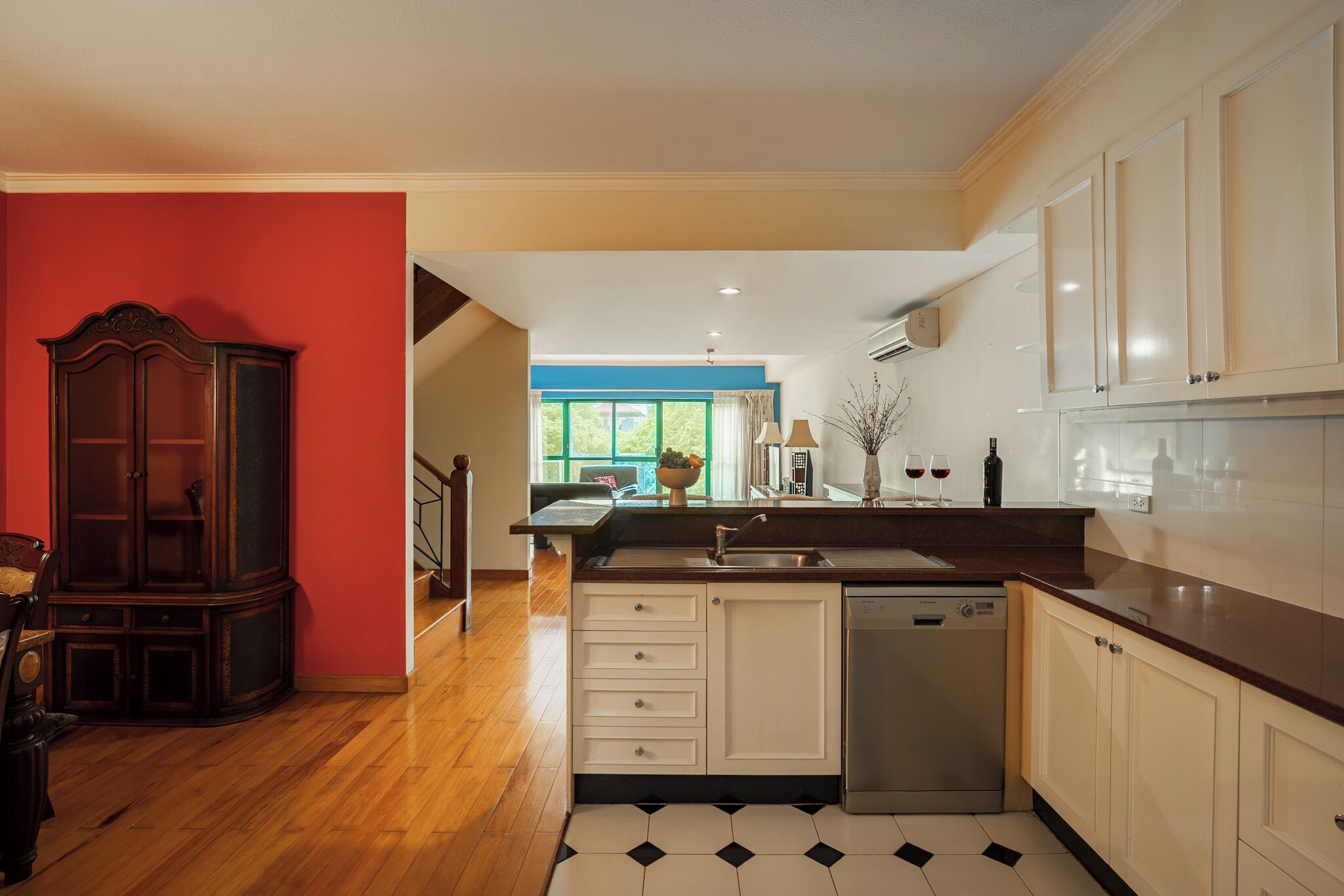 A kitchen with a dishwasher, a sink, and a dining area with a table and chairs.