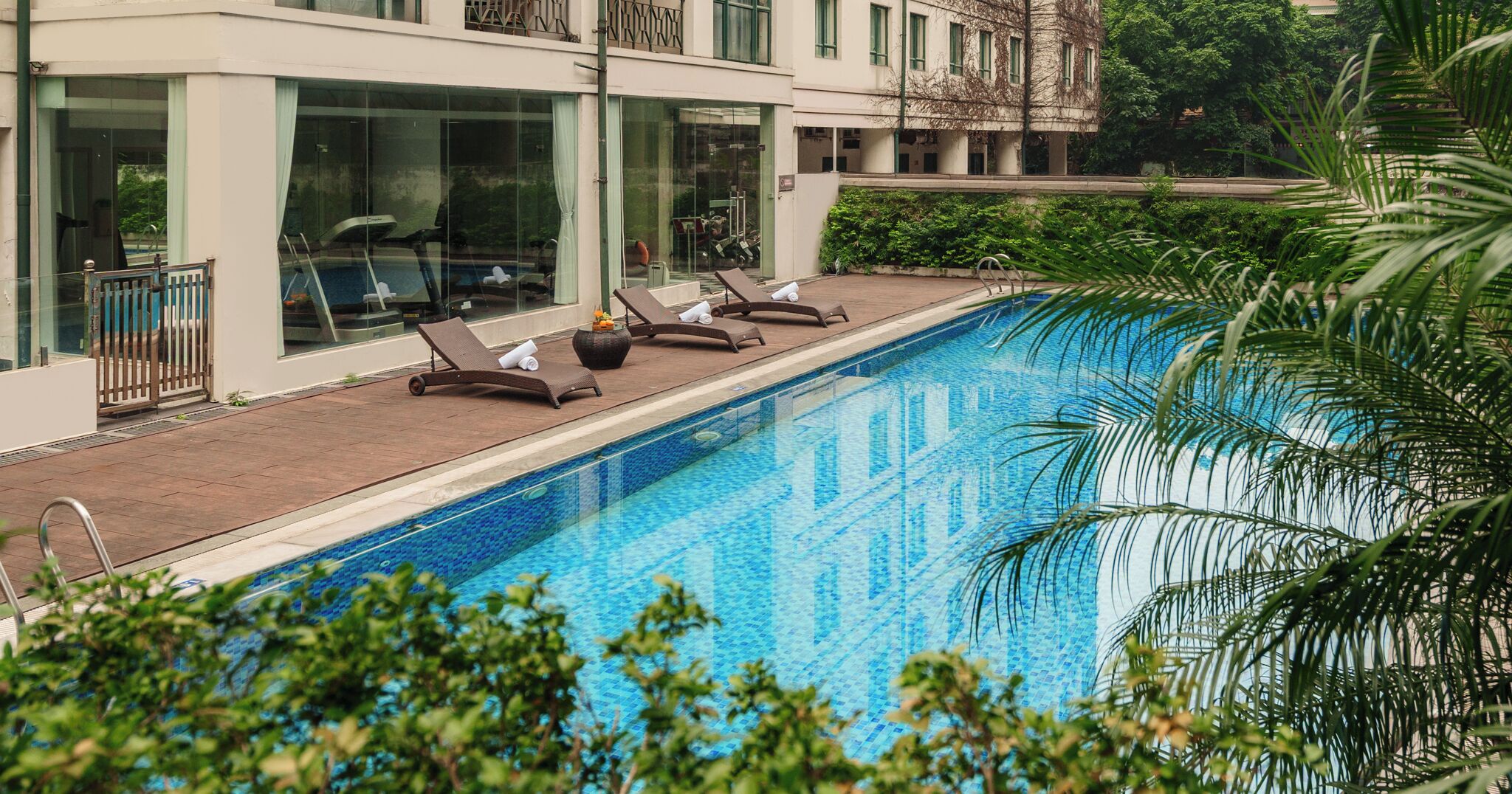 Ein Swimmingpool mit Liegestühlen und ein Gebäude mit großen Fenstern im Hintergrund.