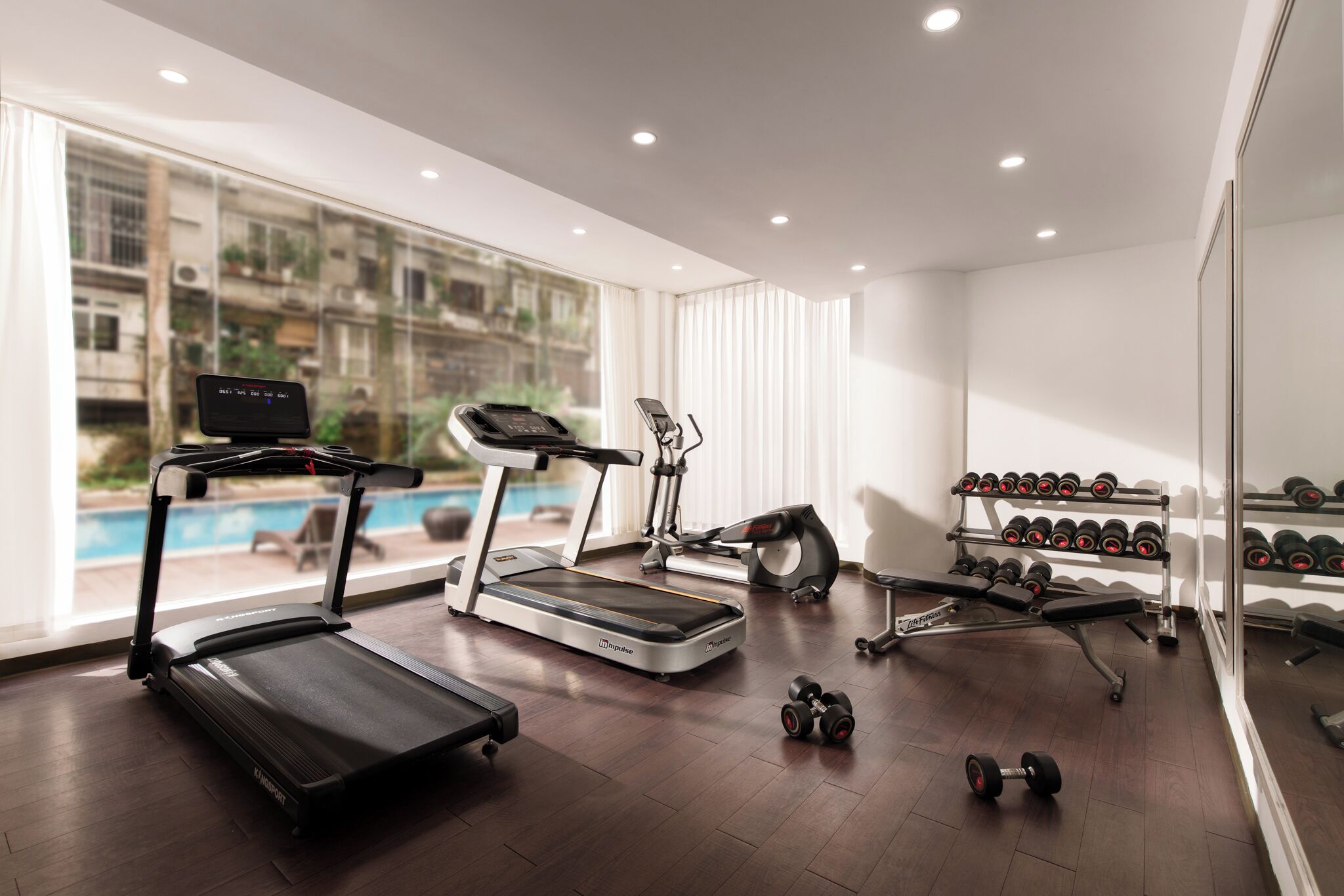Un gimnasio moderno con cintas de correr, elíptica y equipo de press de banca.