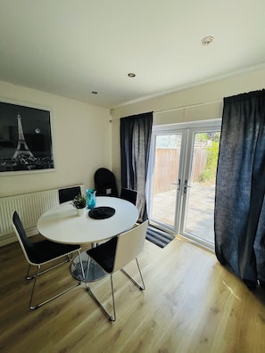 A dining area with a round table, black chairs, a potted plant, and a painting of the Eiffel Tower. - Spacious House | Sleeps 10 | 15mins to LDNcentre | 3 Private Parking Spots (London)