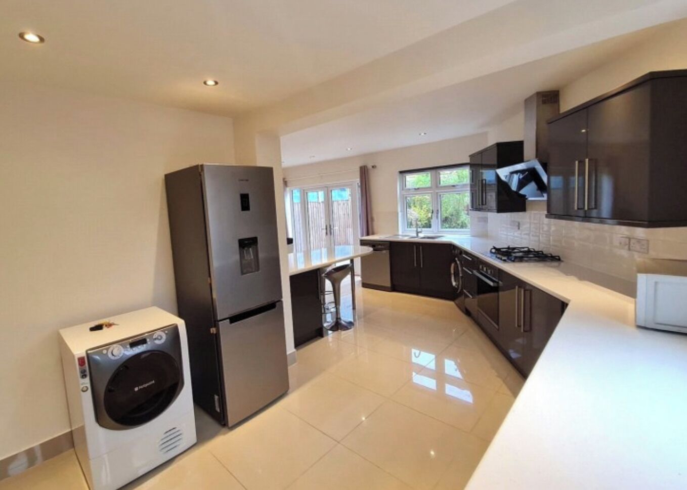 A modern kitchen with a built-in oven, a washing machine, and a large window providing natural light.