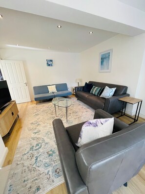 A living room with a sofa, armchair, and a coffee table. - Spacious House | Sleeps 10 | 15mins to LDNcentre | 3 Private Parking Spots (London)
