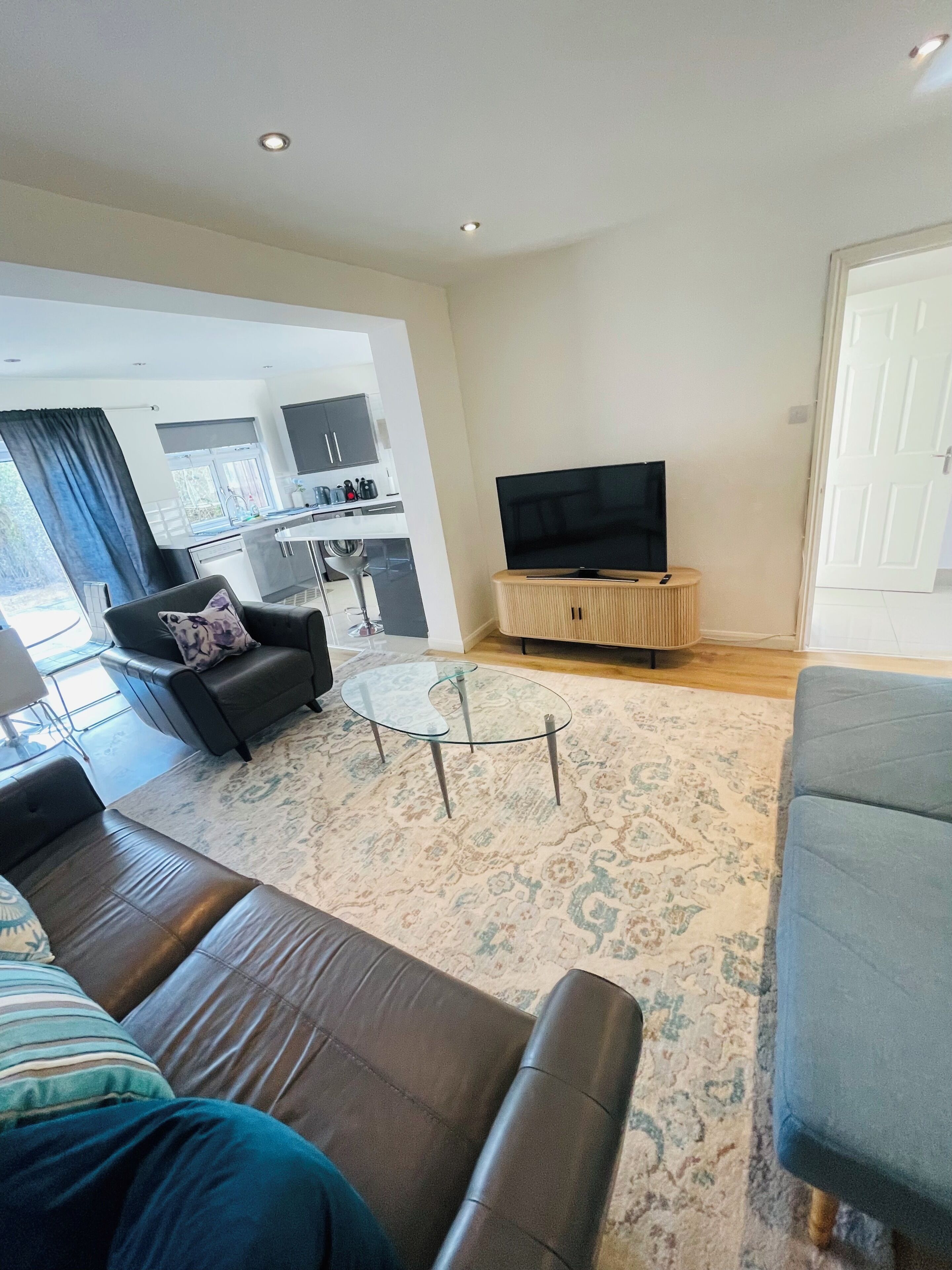 A living room with a sofa, a glass coffee table, and a television on a wooden stand.