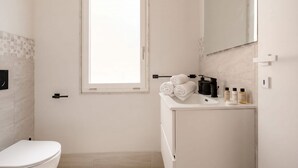 Une salle de bain avec des toilettes, un lavabo, un miroir et une fenêtre.