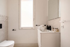 Ein Badezimmer mit Toilette, Waschbecken, Spiegel und Fenster.
