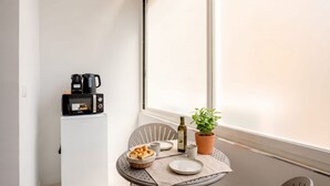 Une petite cuisine équipée d’un four à micro-ondes, d’une machine à café et d’une plante en pot posée sur une table.