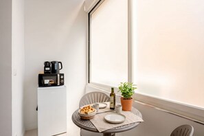Eine kleine Küchenzeile mit Mikrowelle, Kaffeemaschine und einem Blumentopf auf einem Tisch.