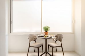 A small dining area with a round table and two chairs, a potted plant, and a window with a view. - City Hub 6 | Historic Elegance & Modern Comfort in Bari (Bari)