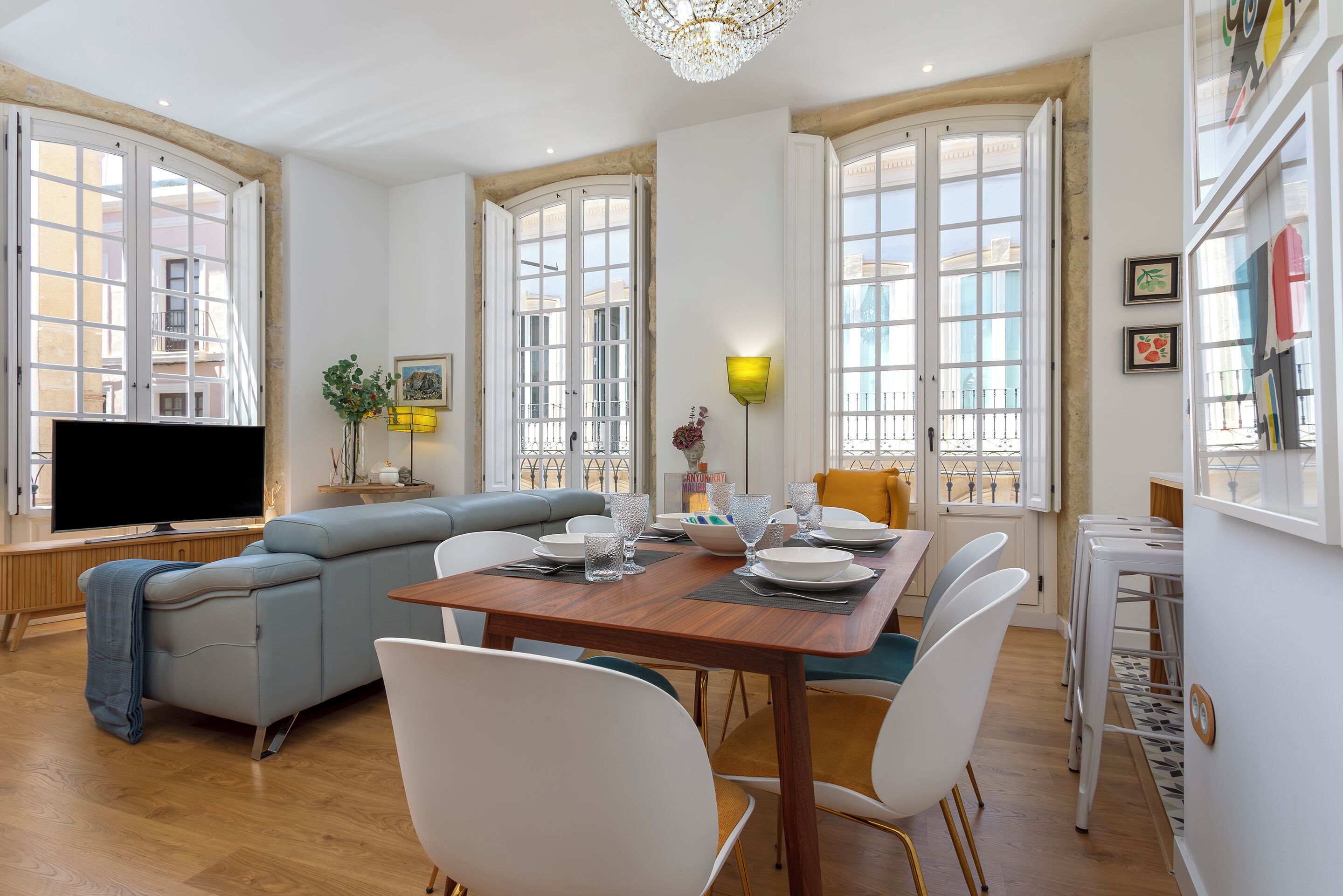 A modern living space with a dining area, a sofa, and a television.