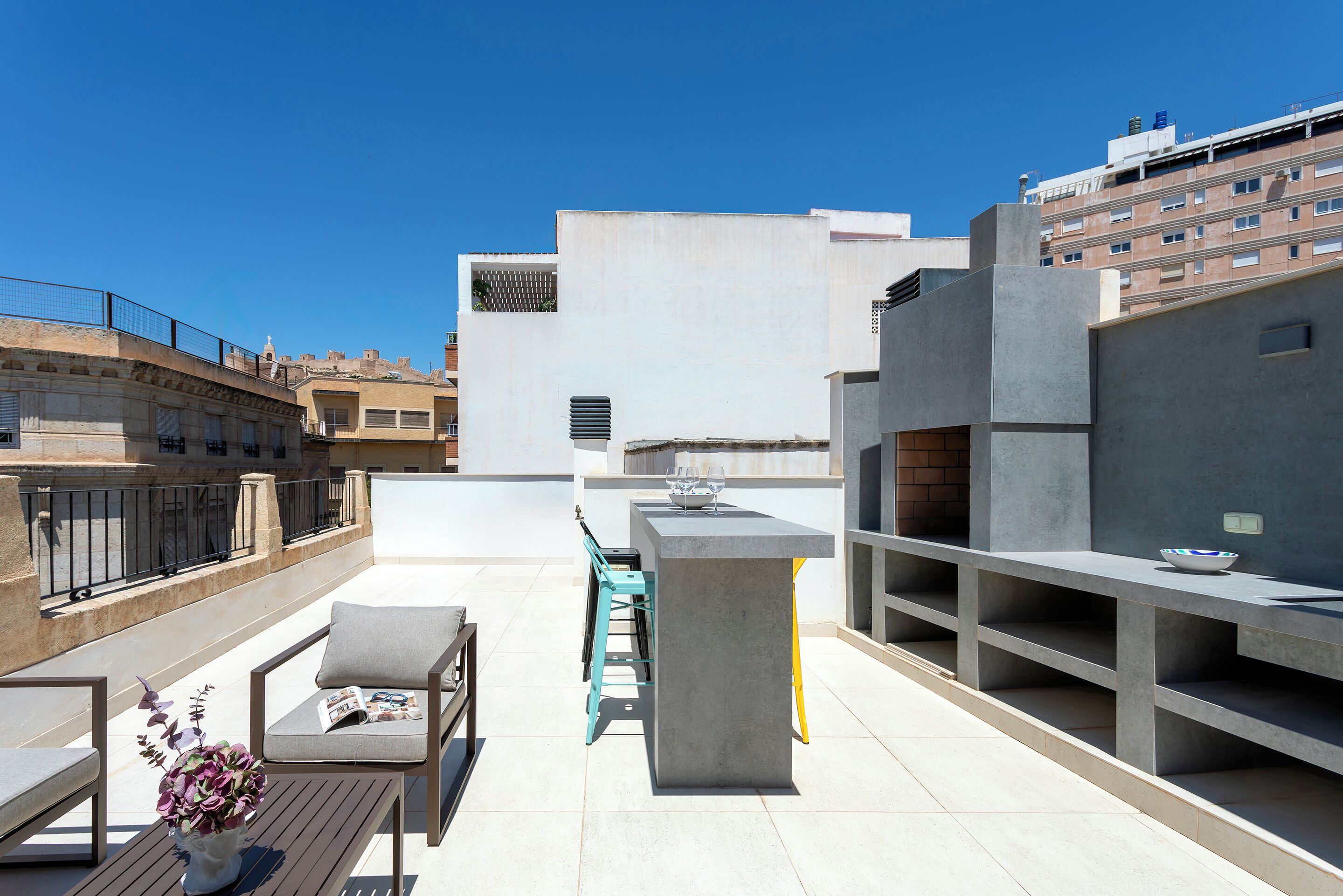 Terraço no telhado com área de bar, assentos e vista da paisagem urbana.