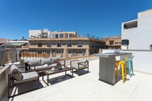 Une terrasse sur le toit avec des sièges extérieurs, une table en béton et une chaise jaune.