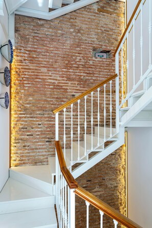 Eine Treppe mit weißen Balustraden und Holzbalken an einer Ziegelwand.