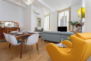 A modern living room with a sofa, yellow armchair, dining table with chairs, and a TV. - Genteel Home House of the 12 Balconies (Almeria)