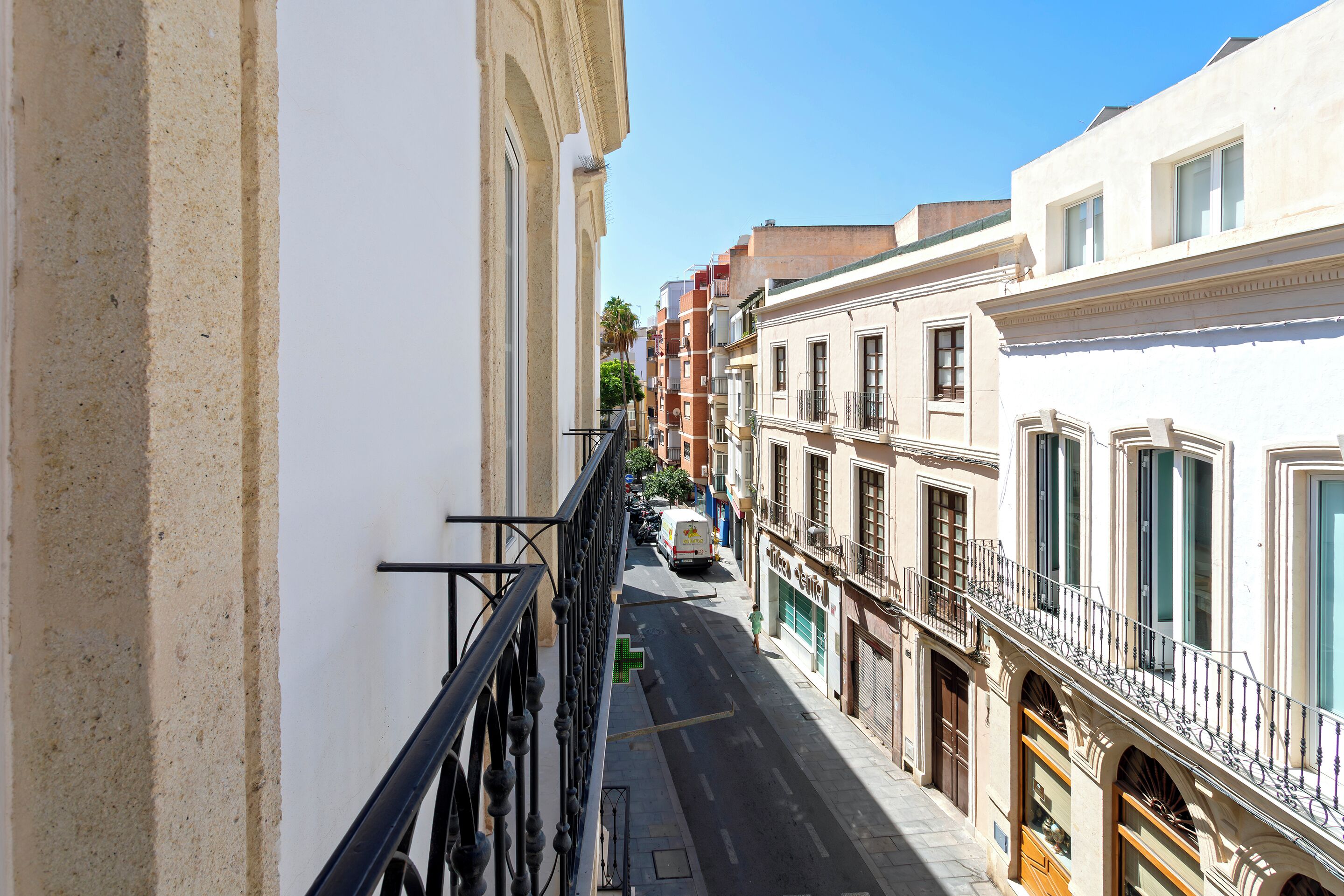 A narrow street with buildings on both sides, a pedestrian walkway, and a parked van.