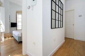 A hotel room with a bed, a television, a wall-mounted telephone, and a door with a nameplate. - Genteel Home House of the 12 Balconies (Almeria)