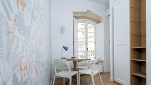 Et værelse med et spisebord, stole, en lampe, en vægmonteret skulptur og et træskab.