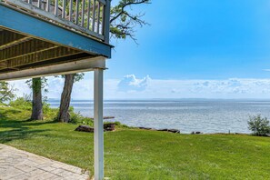 Une propriété située sur la côte, dotée d’une terrasse avec vue sur la mer, d’une pelouse verdoyante et d’un ciel dégagé.