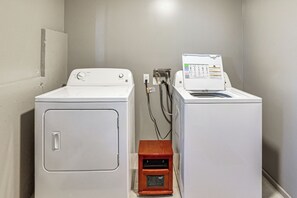 Une buanderie équipée de deux machines à laver blanches et d’un sèche-linge en bois.