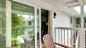 Une chaise en bois sur un porche, avec une porte vitrée donnant sur un balcon.
