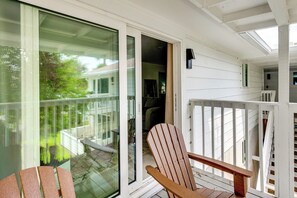 Ein Holzstuhl auf einer Veranda mit einer Glastür, die zu einem Balkon führt.