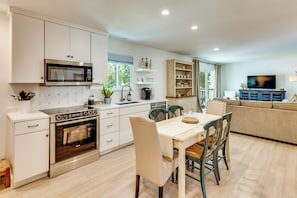 A modern kitchen with a Bosch oven, a microwave, and a dining area with a table and chairs. - Walk to Beach! Atlantic Beach Extended Stay (Atlantic Beach)