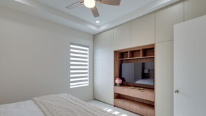 Ein Schlafzimmer mit Bett, Kleiderschrank, Deckenventilator und einem Fenster mit Jalousien.