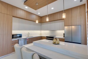 A modern kitchen with wooden cabinets, stainless steel appliances, and pendant lighting.