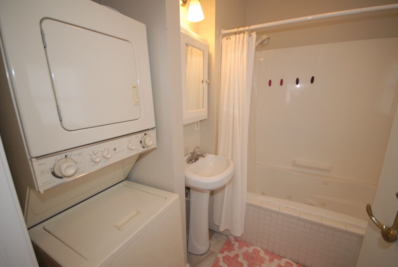 Une salle de bain équipée d’un lave-linge, d’un évier et d’une baignoire.