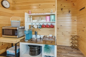 A kitchenette with a microwave, coffee maker, and storage shelves.