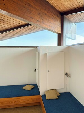Ein Zimmer mit zwei Betten, Holzbalkendecke und einem Oberlicht.