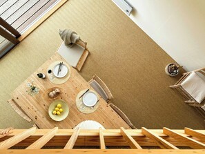 Une table de salle à manger en bois, sur laquelle repose un tapis tressé, un bol de citrons et une petite plante.