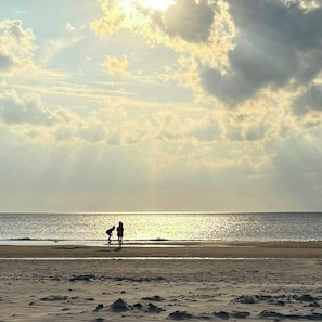 Une plage avec un ciel dégagé et quelques nuages.