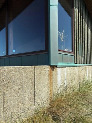 Ecke eines Gebäudes mit Fenster, Holzverkleidung und einer Betonwand.