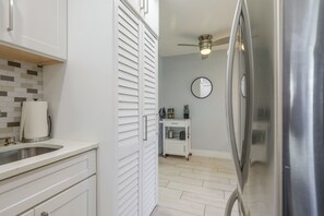 Eine moderne Küche mit weißen Schränken, einem Edelstahlkühlschrank und einem Deckenventilator.