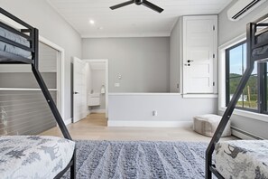 Een moderne slaapkamer met een stapelbed, een plafondventilator en uitzicht op het omliggende landschap.