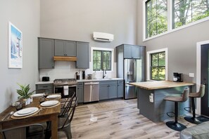 Een moderne keuken met grijze kastjes, een roestvrijstalen koelkast en een houten kookeiland met barkrukken.