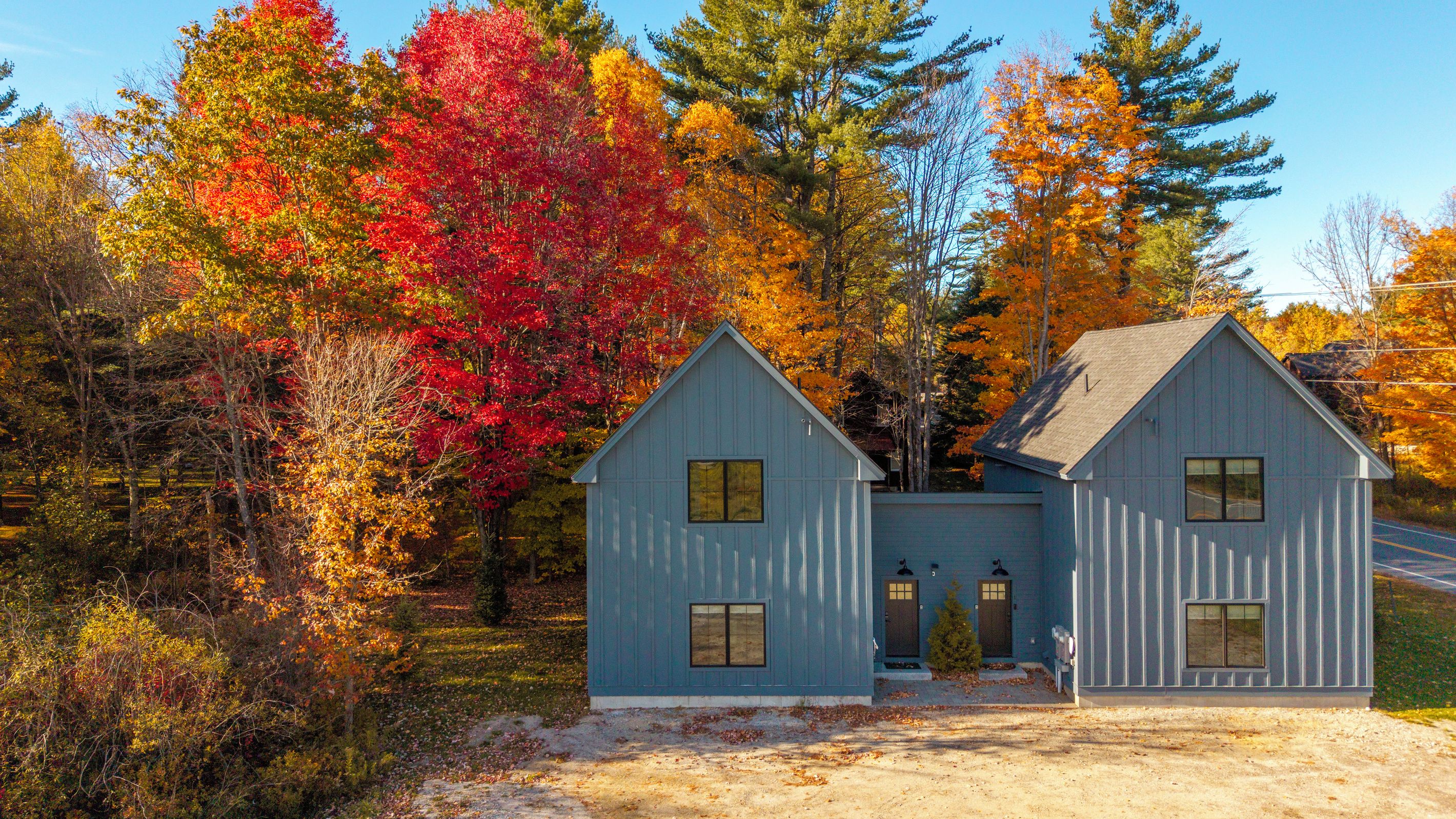 Una casa di legno blu a due piani, con un design simmetrico, un camino centrale e un piccolo portico.