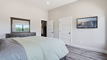 A bedroom with a bed, dresser, and a television on the wall.