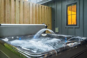 Een hottub met een houten omheining en een raam met geel licht.