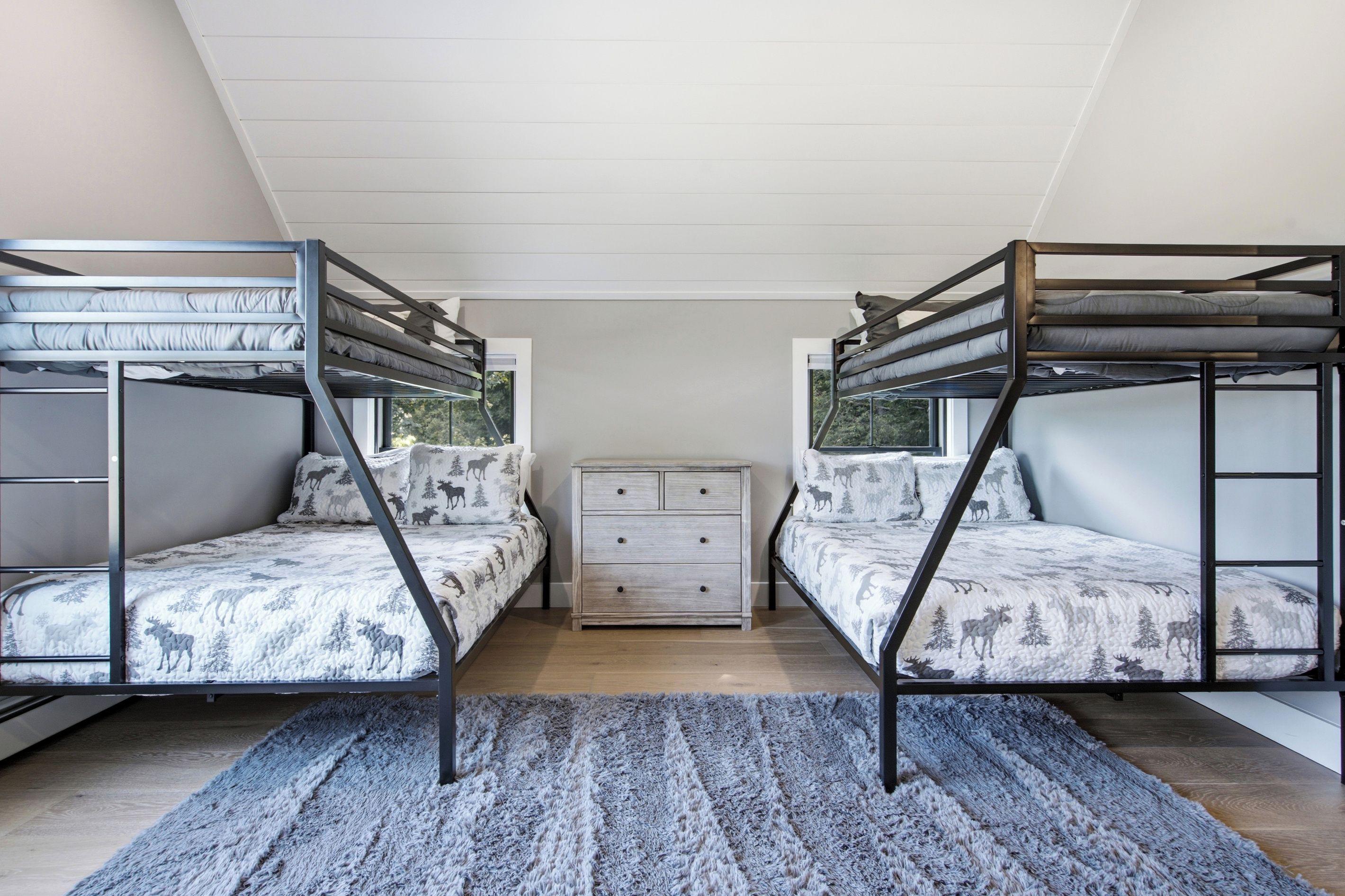 Une chambre avec deux lits superposés, une commode et un tapis.