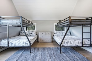 Une chambre avec deux lits superposés, une commode et un tapis.