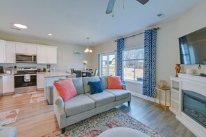 Ein modernes Wohnzimmer mit einem grauen Sofa, einem gemusterten Teppich und einem Kamin.