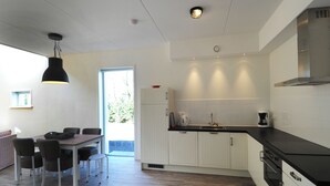 A modern kitchen with white cabinets, a black countertop, and a dining area with a table and chairs.