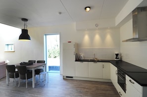 Una cucina moderna con mobili bianchi, un piano di lavoro nero e un'area pranzo con tavolo e sedie.