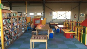 A library with bookshelves, a chess table, and colorful play areas.