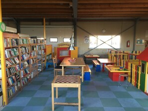 Ett bibliotek med bokhyllor, ett schackbord och färgglada lekytor.