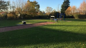 A park with a playground, a picnic table, and a walking path.