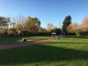 Un parc amb un espai de jocs, una taula de pícnic i un camí per passejar.