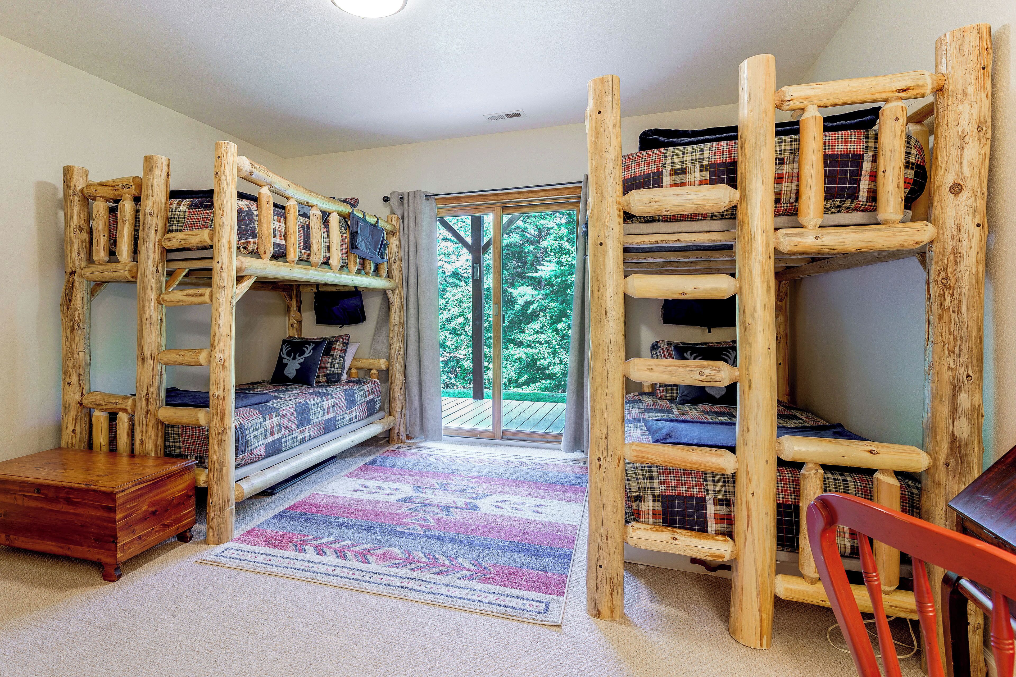 A room with a bunk bed, a desk, and a window with a view of trees.