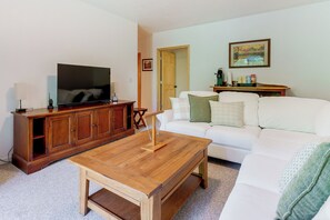 A living room with a television, wooden cabinet, white sofa, and a coffee table. - Serene Wooded Cabin w/ Decks, 4 Mi to Dtwn Murphy (Murphy)